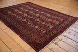 Cherry red Pakistani Belouch rug corner, highlighting fine vinery border and detailed boteh patterns.