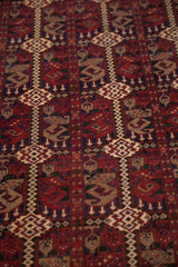 Pakistani Belouch rug pattern with cherry red botehs, charcoal navy, and beige vinery.
