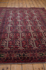 Hand-knotted fringe and cherry red, navy, beige geometric end border on a Belouch design rug.