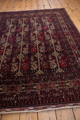 Intact fringe and side cord on Belouch rug corner, with cherry red and navy border.