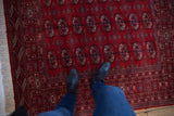 Detailed Bokhara gul medallions and plush, high-sheen pile on a vintage cherry red rug.