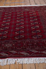 Low-angle view showing the lustrous cherry red pile and intact ivory fringe of a vintage Bokhara rug.
