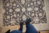 Overhead view of the dense pile and floral vinery on a charcoal and ivory Peshawar rug.