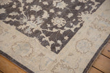 The full, plush pile of a Peshawar rug corner in charcoal, ivory, and powder blue.