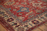 Geometric palmettes in cherry red and sapphire blue on the corner of a Pakistani Caucasian rug.