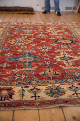 Geometric motifs in sapphire blue and gold on the cherry red field and beige border.