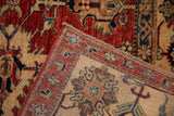 Folded hand-knotted Pakistani Caucasian carpet corner with intact red selvage and geometric motifs.