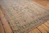 Detailed blue geometric weave and tonal abrashes on a sand and camel Pakistani rug.