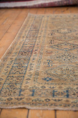 Detailed geometric border and pattern in blue and neutral tones on a Caucasian rug.