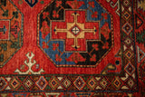 Ersari rug detail: geometric cross motif with diamond border in cherry red, sapphire blue.