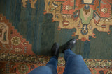 Close-up of vintage Serapi Indian Soumac rug with dusty teal abrash and terra cotta motifs.