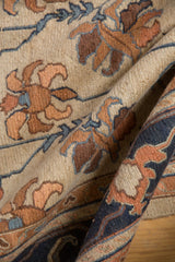 Detailed hand-woven Soumac texture with navy border and terracotta Serapi floral motifs.