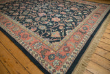 Corner view of vintage Indian Soumac rug with dusty blush border and navy vinery.