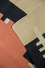 Hand woven contemporary Kilim rug runner in sand, black, and red geometric blocks, showing intact selvage.