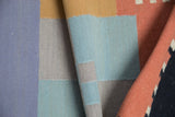 Folded contemporary kilim rug, showing flatweave texture with powder blue, sand, and madder red.