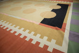 Abstract contemporary Kilim rug with beige circles, black rectangle, and stepped terracotta patterns.