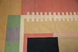 Abstract geometric detail of the Contemporary Kilim rug with black, coral, and beige blocks.