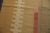 Close-up of hand-woven Kilim's abstract stepped pattern in beige, ivory, and madder red.