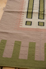 Contemporary Kilim rug with geometric pale green, beige, and raspberry striped patterns.