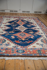 Secured original white fringe and rust, blue floral border of a Northwest Persian carpet.