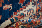 Folded hand-knotted Persian rug, showing plush pile and vibrant navy, ivory, and rust patterns.