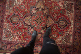 A point-of-view shot standing on the geometric cherry red and navy medallion of a vintage Heriz rug.