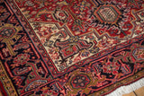 Detailed corner of a vintage Persian Heriz rug with serrated leaf motifs in the navy and red border.