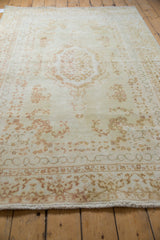 Hand-knotted fringe and curvilinear border pattern in ivory and pale coffee tones.