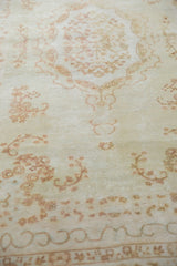 Even, short pile showing Rococo curvilinear motifs and floral sprays in ivory and pale coffee brown.