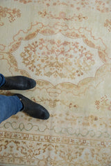 Ivory vintage Bulgarian rug with Rococo scalloped outline and pale floral spray motifs.