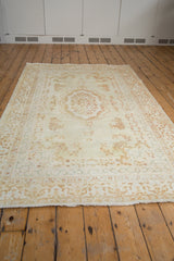 Traditional vintage Kerman rug with ivory field, Rococo medallion, and pale coffee floral sprays.