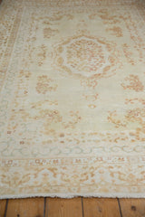 Ivory Kerman rug with pale coffee Rococo floral patterns and decorative border.