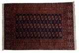Vintage Pakistani Bokhara carpet with repeating rust gul medallions on a rich navy blue field.