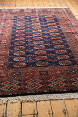 Angled view of a vintage Bokhara design carpet highlighting the plush, high-sheen wool pile.