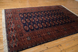 Full perspective view of a vintage Pakistani Bokhara rug with a repeating gul pattern in navy and rust.