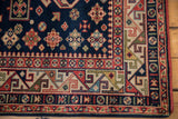 Vintage Romanian Kuba carpet corner, displaying colorful geometric borders and navy diamond motifs.