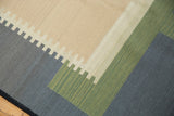 Hand woven abstract contemporary Kilim rug showing stepped beige, charcoal, and green patterns.