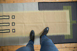 Flatweave contemporary Kilim rug with abstract beige, charcoal, and light green geometric patterns.