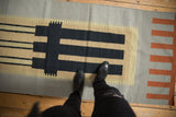 Architectural geometric kilim runner featuring silver, black, terracotta blocks, and feet.
