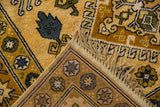 Folded corner of Siberian Caucasian rug, showing saffron, blue geometric motifs, fringe, and hand-knotted back.