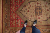 Hand-knotted Chinese Khotan rug with fringe, brick red border, and scalloped ivory field.