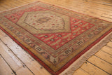 Dusty brick red field with gold floral motifs, geometric borders, and original selvage on Khotan carpet.