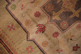 Plush beige pile, scalloped medallion contour, and floral motifs in aubergine and brick red.