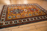 Saffron field, meandering vine, and pawn design border of a Vintage Siberian Kazak rug.