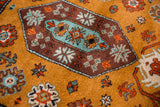 Vintage Siberian Kazak rug detail: plush ochre field with chocolate, powder blue, and tangerine motifs.