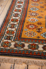 Siberian Kazak rug corner: ochre field, vibrant floral top views, cream meandering vine, pawn borders.