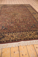 Dark beige field of vintage Romanian Tabriz rug with scrolling vinery, navy border, ivory fringe.