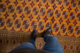 Looking down at the fine weave of red gul medallions on a vintage tangerine Bokhara carpet.