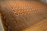 Angled view of a vintage Bokhara rug showing the lush tangerine pile and repeating geometric guls.