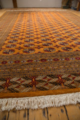 Long view across the tangerine orange field and intricate border of a vintage Bokhara rug.